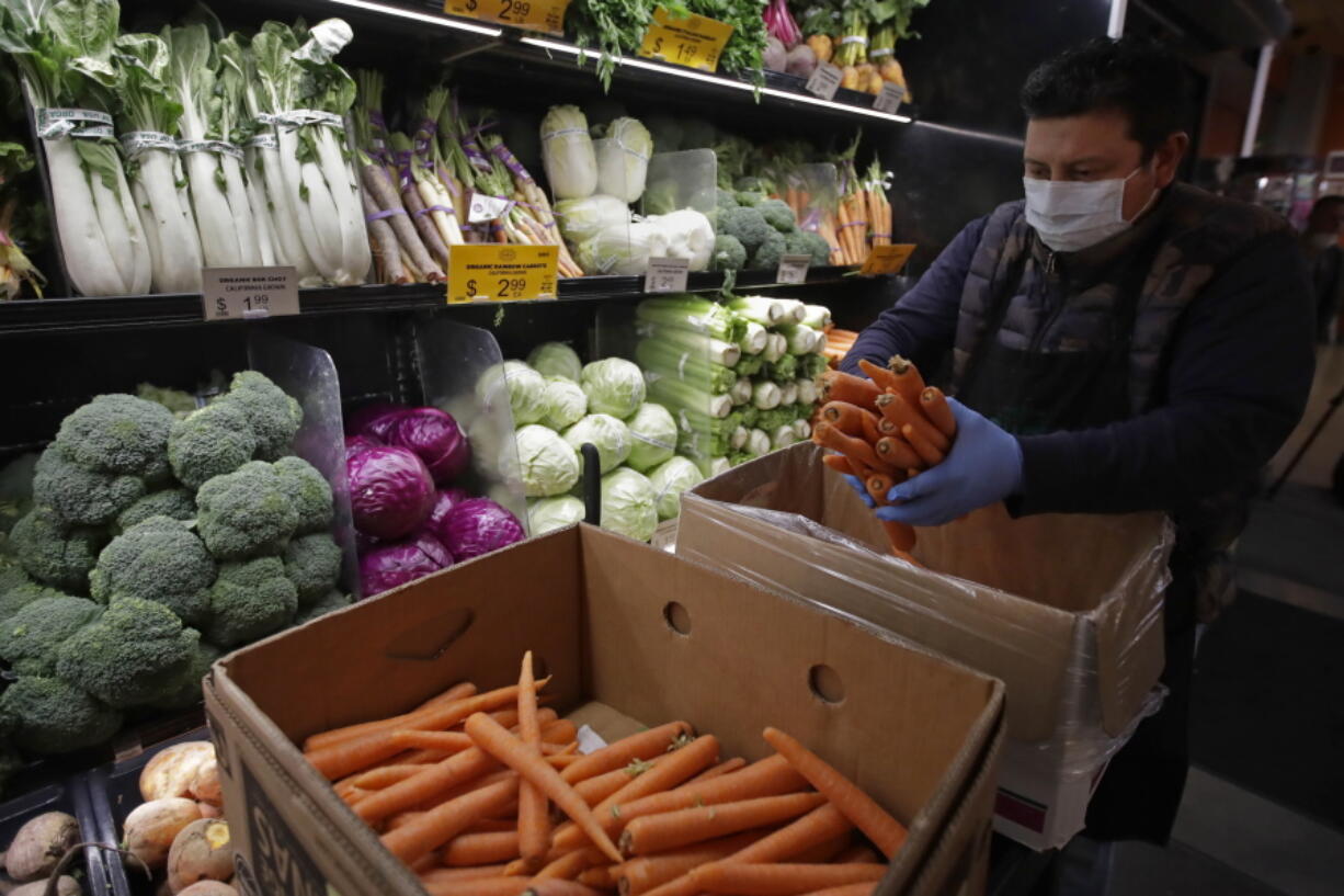 FILE - A worker stocks produce before the opening of a market in San Francisco on Friday, March 27, 2020. On Thursday, Nov. 17, 2022, U.S. agriculture officials proposed changes to the federal program that helps pay the grocery bills for pregnant women, babies and young children that includes keeping a bump in payments for fresh fruits and vegetables allowed during the COVID-19 pandemic.