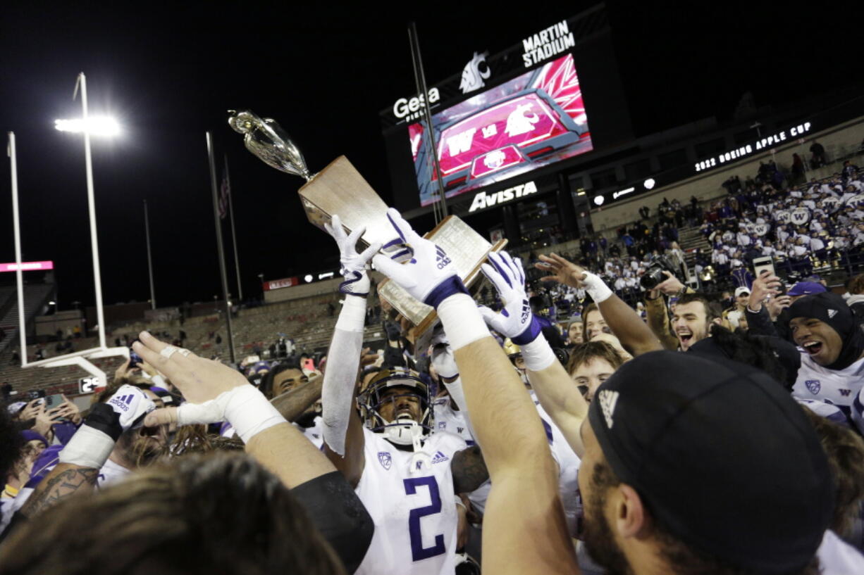 Washington players celebrate with the Apple Cup Trophy after their 51-33 win against Washington State on Saturday in Pullman.