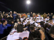 FILE - Bremerton assistant football coach Joe Kennedy, obscured at center in blue, is surrounded by Centralia High School football players as they kneel and pray with him on the field after their game against Bremerton on Oct. 16, 2015, in Bremerton, Wash. After losing his coaching job for refusing to stop kneeling in prayer with players and spectators on the field immediately after football games, Kennedy will take his arguments before the U.S. Supreme Court on Monday, April 25, 2022, saying the Bremerton School District violated his First Amendment rights by refusing to let him continue praying at midfield after games. (Meegan M.