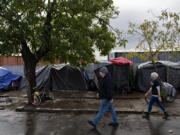 Jacob Phillips, left, and Tiffany Mercer of XChange's Street Medicine Team stroll past tents to offer medical assistance to those living near the Share House on a Wednesday morning in October.