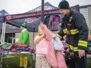 Vancouver firefighter Matt Hankins, right, helps Marshall Elementary second-grader Leilani Beck try on a coat at Marshall Elementary School. Members of Vancouver Fire Local 542 handed out donated coats to students who needed them.