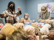 Volunteers Andrea Nelson, left, Terri Pedigo and LaVonne Crimm work on making weighted teddy bears Wednesday, as part of a toy drive at The Children's Center in Vancouver.