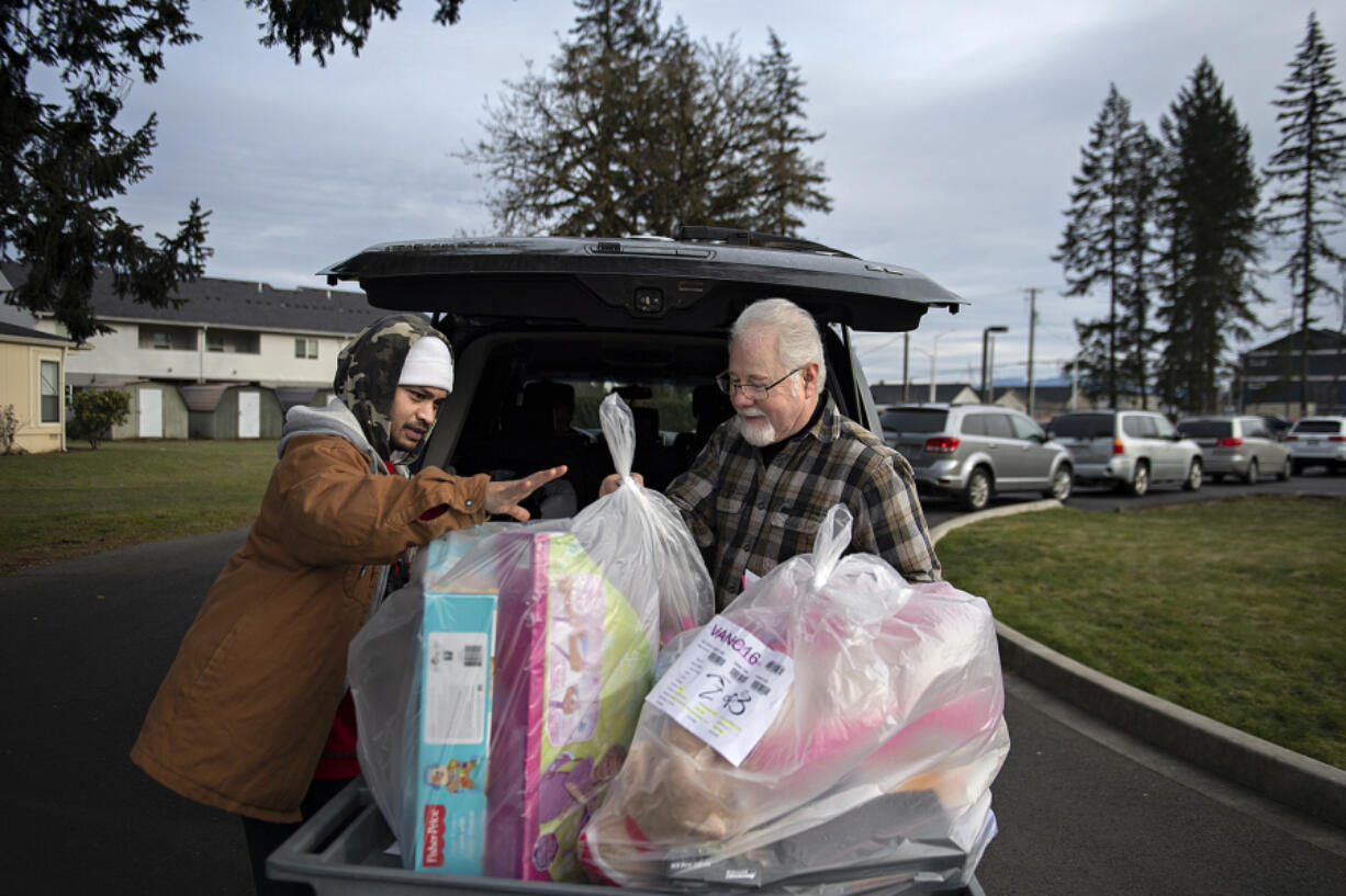 Vancouver resident Aston Astonishment picks up Christmas gifts while assisted by volunteer Jon Sholer at The Salvation Army on Thursday morning. The Salvation Army assisted 800 local families and nearly 2,000 children this Christmas.