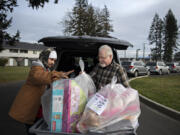 Vancouver resident Aston Astonishment picks up Christmas gifts while assisted by volunteer Jon Sholer at The Salvation Army on Thursday morning. The Salvation Army assisted 800 local families and nearly 2,000 children this Christmas.