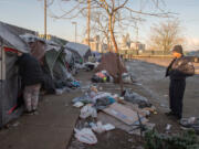 Vancouver Police Officer Tyler Chavers, a member of the city's Homeless Assistance and Resources Team, talks with people living at a homeless encampment near Share House in downtown Vancouver.