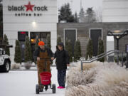 Jerrod Ailshie of Pup Creek Excavation joins his wife, Sara, as they add a layer of ice melting substance around the front pathway of a bank in southeast Vancouver on Friday morning, Dec. 23, 2022. The couple, who live in Woodland, started their day at 4:30 am to help plow roads and help people get around safely.