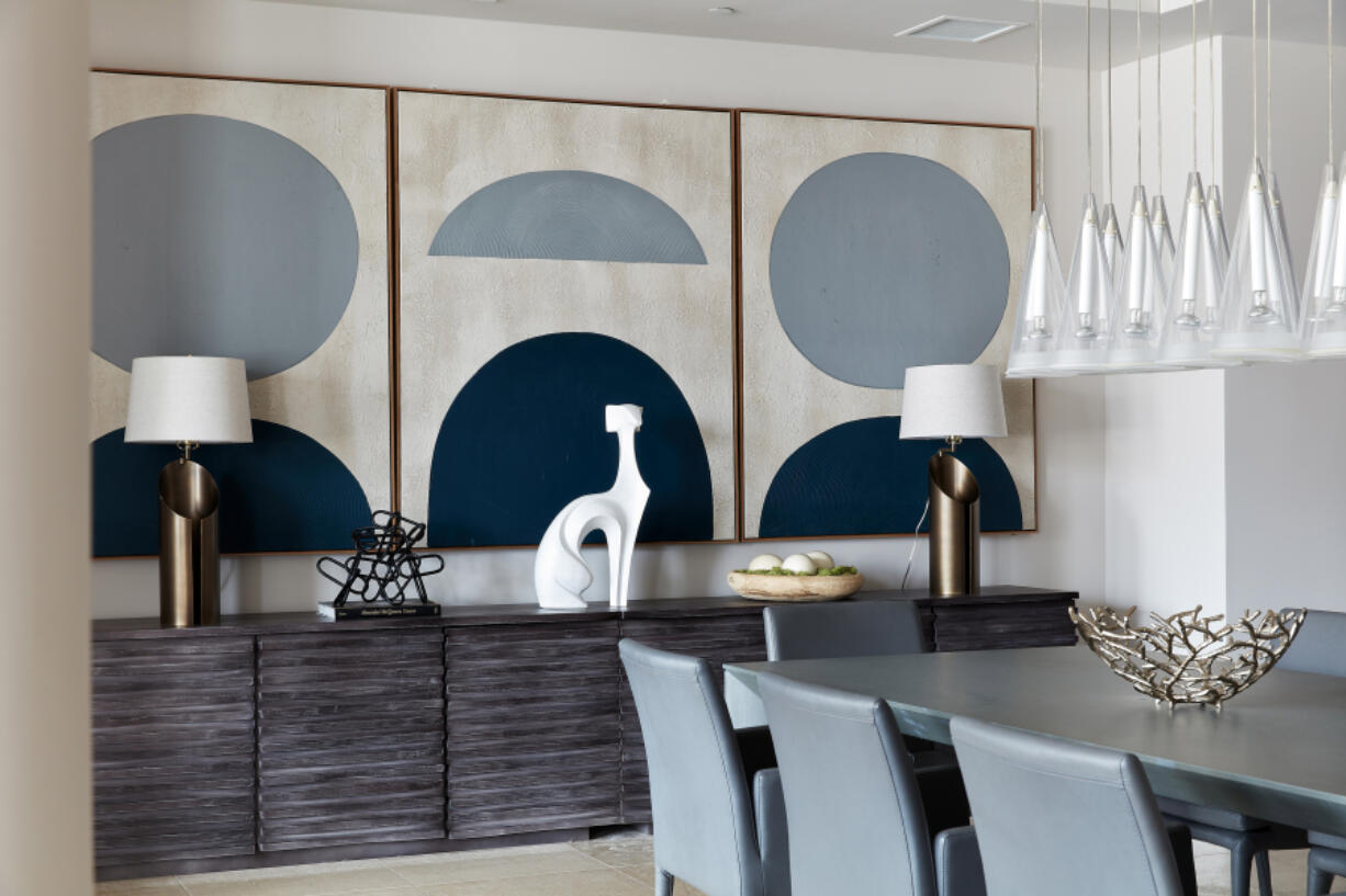 Three pieces of art hung in a series helps add rhythm to this dining room area.