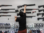 An employee puts back a gun for sale at Wade's Eastside Guns in Bellevue on Monday, Aug. 22, 2022.