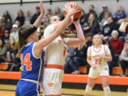 Washougal’s Hadley Jones, center, puts up a shot while being guarded by Ridgefield’s Morgan Goode, left, during a 2A GSHL girls basketball game on Wednesday, Dec. 14, 2022, at Washougal High School.