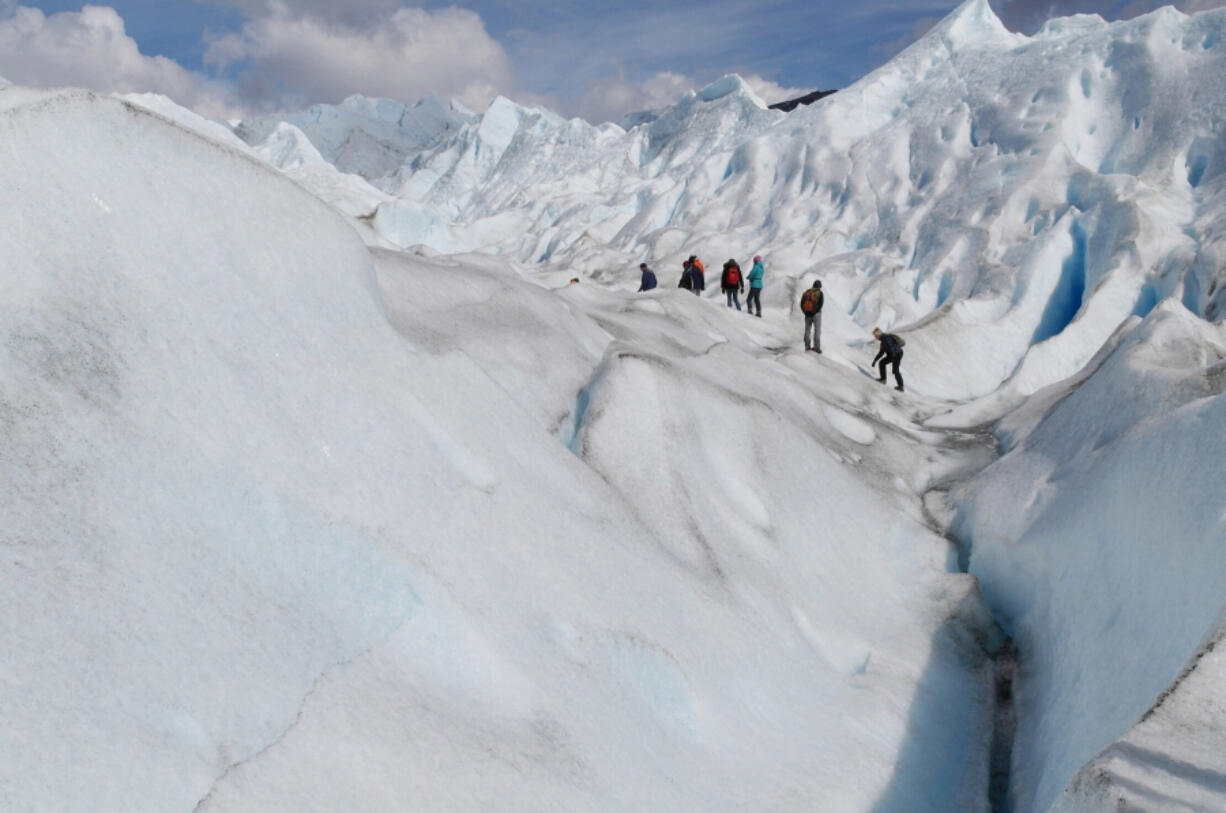 Hikers make their way across a glacier.