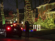 A woman takes a picture of a house decorated with holiday lights on Dec. 10 in Lincolnwood, Ill. (John J.