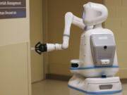 Moxi lowers its arm in order to push a button to open a door as it delivers supplies at Elmhurst Hospital on Dec. 1, 2022.