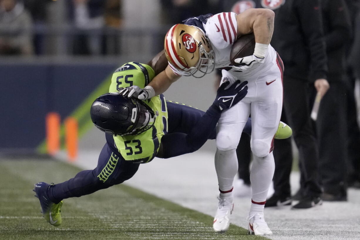 San Francisco 49ers running back Christian McCaffrey, right, runs against Seattle Seahawks linebacker Boye Mafe (53) during the first half of an NFL football game in Seattle, Thursday, Dec. 15, 2022.