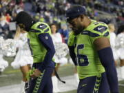 Seattle Seahawks cornerback Coby Bryant, left, and linebacker Jordyn Brooks walk off the field after an NFL football game against the San Francisco 49ers in Seattle, Thursday, Dec. 15, 2022.