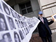 Paul Hudson of Sarasota, Fla., holds up a photo of his daughter Melina who was killed at 16 years old along with the photos of almost a hundred other victims of the bombing of Pan Am Flight 103 over Lockerbie, Scotland, as he speaks to members of the media in front of the federal courthouse in Washington, Monday, Dec. 12, 2022. The Justice Department says a Libyan intelligence official, Abu Agila Mohammad Mas'ud Kheir Al-Marimi, accused of making the bomb that brought down Pan Am Flight 103 over Lockerbie, Scotland, in 1988 in an international act of terrorism has been taken into U.S. custody and will face federal charges in Washington.