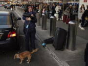 Two people hug outside a terminal as travelers wait in line to check in at Los Angeles International Airport in Los Angeles, Monday, Dec. 19, 2022. (AP Photo/Jae C.