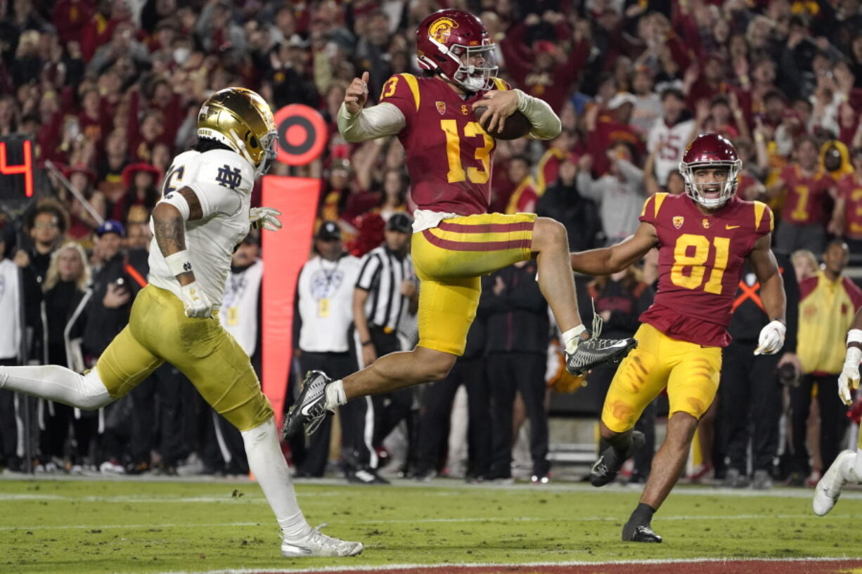 FILE - Southern California quarterback Caleb Williams jumps in for a touchdown as Notre Dame safety Xavier Watts, left, defends and Southern California wide receiver Kyle Ford watches during the second half of an NCAA college football game Saturday, Nov. 26, 2022, in Los Angeles. Southern California quarterback Caleb Williams was named the AP Player of the Year in college football, Thursday, Dec. 8, 2022. (AP Photo/Mark J.