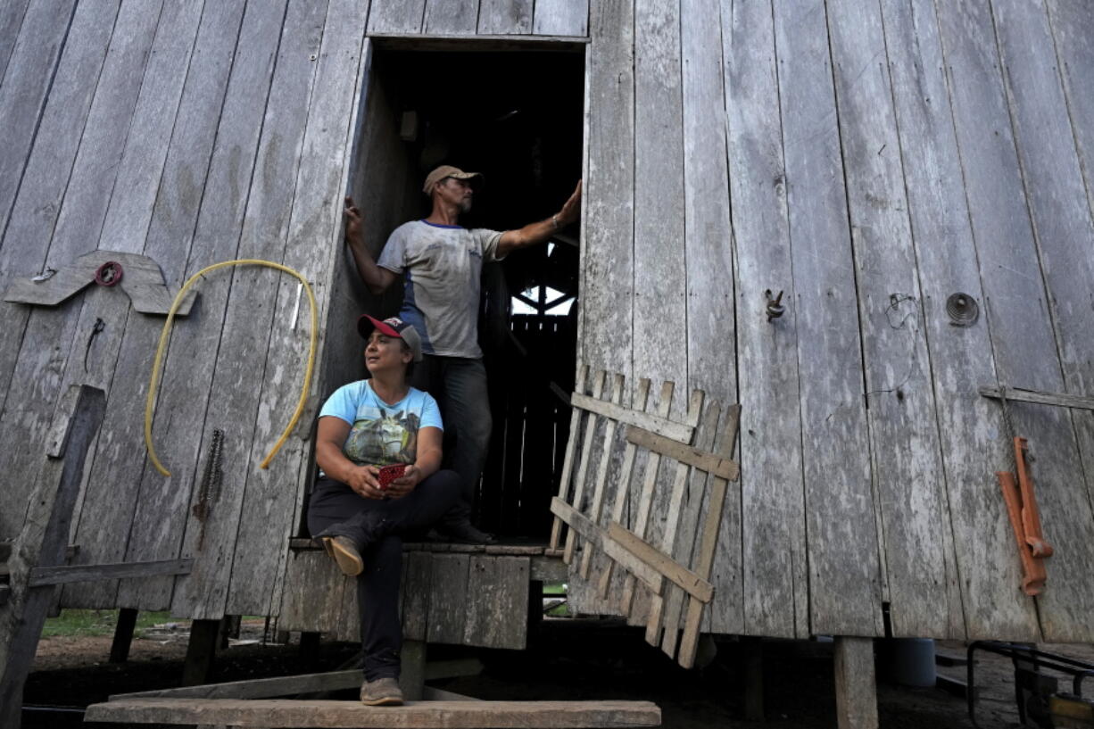 Rubber-tapper Luzineide Marques da Silva and her husband Eneas Souza Campos appear at the door of their house in the Chico Mendes Extractive Reserve, in Xapuri, Acre state, Brazil, Tuesday, Dec. 6, 2022. Classic rubber tapping is done by slicing grooves into the bark of rubber trees and collecting the latex that oozes out. But that artisanal rubber has fallen into decline over decades, a casualty of synthetic rubber made in chemical factories or rubber grown on plantations.