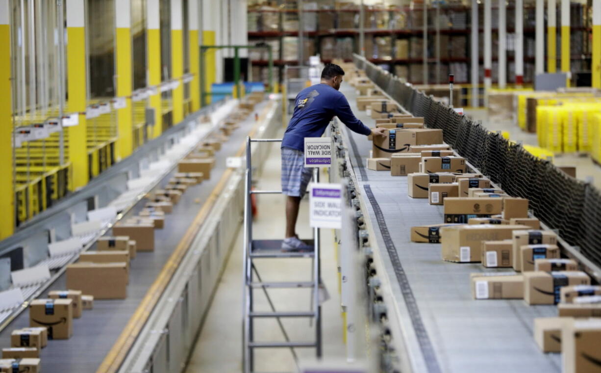 FILE - In this Tuesday, Aug. 1, 2017, photo, an Amazon employee makes sure a box riding on a belt is not sticking out at the Amazon Fulfillment center in Robbinsville Township, N.J. Amazon failed to properly record work-related injuries at warehouses located in five states, a federal agency said Friday, Dec. 16, 2022, while announcing it issued more than a dozen citations during the course of its ongoing investigation of the company.