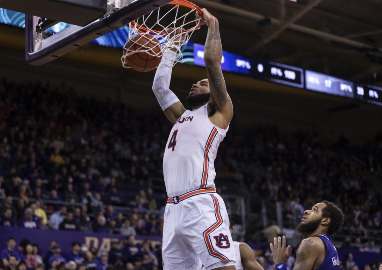 RETRANSMISSION TO CORRECT DAY AND DATE - Auburn forward Johni Broome dunks over Washington guard PJ Fuller II during the first half of an NCAA college basketball game, Wednesday, Dec. 21, 2022, in Seattle.