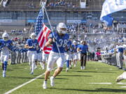 This Oct. 22, 2022, photo provided by University of Buffalo Athletics shows University at Buffalo NCAA college football player Damian Jackson (38) carrying the American flag as the team takes the field before a game against Toledo, in Buffalo, N.Y. Jackson has no expectation of growing emotional in preparing to play the final game of his college career next week.  (Paul Hokanson/Univ.