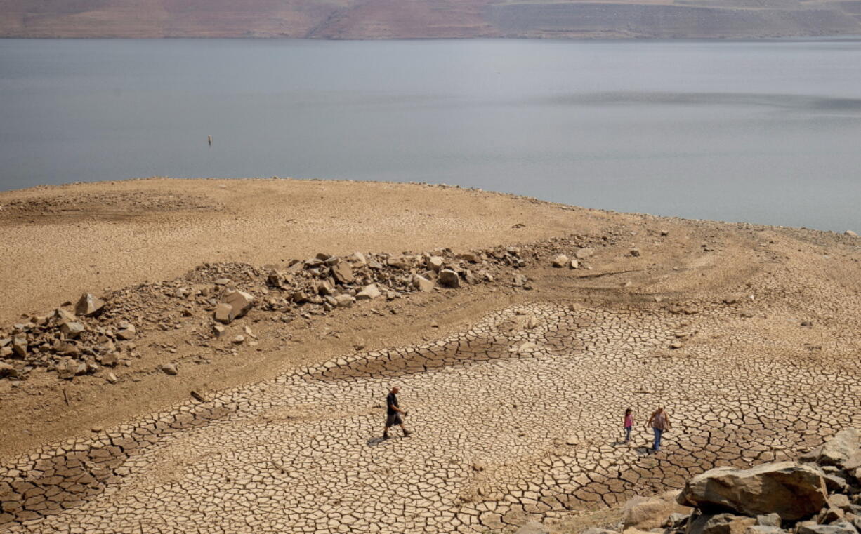 ***HOLD for Story running Wed. Nov. 30, 2022 *** FILE - A family walks over cracked mud near Lake Oroville's shore as water levels remain low due to continuing drought conditions Sunday, Aug. 22, 2021, in Oroville, Calif. Cities and farms that rely on state water supplies will get 5% of what they requested in the new year, state water officials announced Thursday, Dec. 1, 2022.