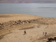 ***HOLD for Story running Wed. Nov. 30, 2022 *** FILE - A family walks over cracked mud near Lake Oroville's shore as water levels remain low due to continuing drought conditions Sunday, Aug. 22, 2021, in Oroville, Calif. Cities and farms that rely on state water supplies will get 5% of what they requested in the new year, state water officials announced Thursday, Dec. 1, 2022.