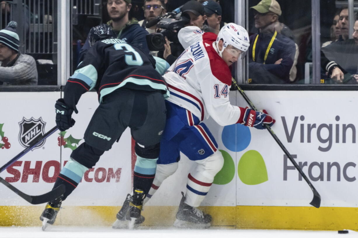 Seattle Kraken defenseman Will Borgen, left, checks Montreal Canadiens forward Nick Suzuki against the boards during the second period of an NHL hockey game Tuesday, Dec. 6, 2022, in Seattle.