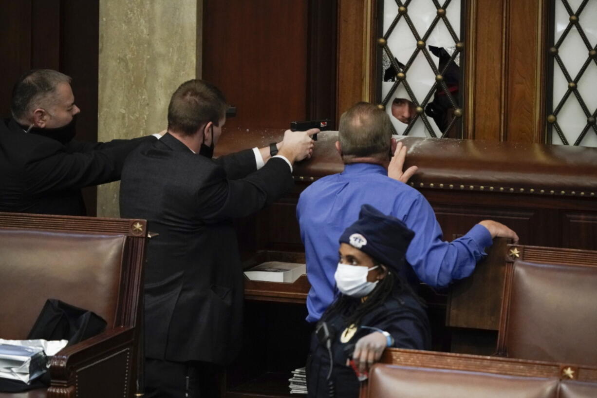 FILE - Police with guns drawn watch as rioters try to break into the House Chamber at the U.S. Capitol on Wednesday, Jan. 6, 2021, in Washington. Top House and Senate leaders will present law enforcement officers who defended the U.S. Capitol on Jan. 6, 2021, with Congressional Gold Medals on Wednesday, Dec. 7, 2022, awarding them Congress's highest honor nearly two years after they fought with former President Donald Trump's supporters in a brutal and bloody attack. (AP Photo/J.