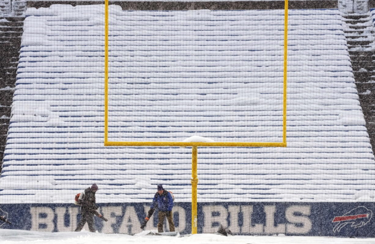 Grounds crew work to clear snow off the field at Highmark Stadium before an NFL football game between the Buffalo Bills and the Miami Dolphins in Orchard Park, N.Y., Saturday, Dec. 17, 2022. (AP Photo/Gene J.