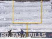 Grounds crew work to clear snow off the field at Highmark Stadium before an NFL football game between the Buffalo Bills and the Miami Dolphins in Orchard Park, N.Y., Saturday, Dec. 17, 2022. (AP Photo/Gene J.