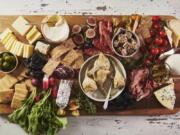 A variety of cheeses, spreads and cured meats are displayed on a graze board. Olives, pickles, and marinated vegetables of all kinds offer a tangy crunch and briney flavor in between bites of cheeses and charcuterie.