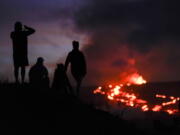 FILE - People watch lava from the Mauna Loa volcano Thursday, Dec. 1, 2022, near Hilo, Hawaii. U.S. scientists declared Tuesday, Dec. 13, 2022, that two active Hawaii volcanoes -- one where lava destroyed hundreds of homes in 2018 and another where lava recently stalled before reaching a crucial Big Island highway -- have stopped erupting.