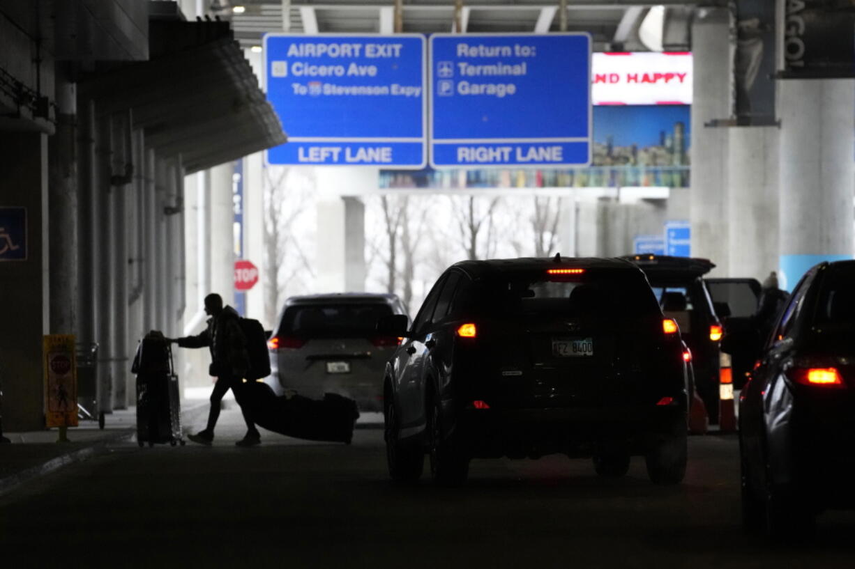 An airline passenger walks between ride share vehicles after arriving at Chicago's Midway Airport just days before a major winter storm Tuesday, Dec. 20, 2022, in Chicago.