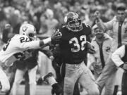 FILE - Pittsburgh Steelers' Franco Harris (32) eludes a tackle by Oakland Raiders' Jimmy Warren as he runs 42-yards for a touchdown after catching a deflected pass during an AFC Divisional NFL football playoff game in Pittsburgh, Dec. 23, 1972. Harris' scoop of a deflected pass and subsequent run for the winning touchdown -- forever known as the "Immaculate Reception" -- has been voted the greatest play in NFL history. On the 50th anniversary of the "Immaculate Reception" -- Friday, Dec. 23, 2022 -- Pittsburghers recall how it boosted morale during the collapse of the steel industry and has served as a cultural rallying point ever since.