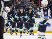 Seattle Kraken left wing Jared McCann (19) leads the team to the bench while celebrating after his goal against the Winnipeg Jets during the third period of an NHL hockey game, Sunday, Dec. 18, 2022, in Seattle.