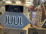 FILE - A Juul sign hangs in the front window of a bodega convenience store in New York City on June 25, 2022. Electronic cigarette maker Juul Labs has reached settlements covering more than 5,000 cases brought by about 10,000 plaintiffs related to its vaping products. Financial terms of the settlement were not disclosed, but Juul said that it has secured an equity investment to fund it. The company has been buffeted by lawsuits and chances that it would seek bankruptcy protection, or a buyer, were elevated last month as Juul announced hundreds of layoffs and secured new financing to  continue operations.