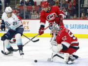 Seattle Kraken's Alex Wennberg (21) watches Carolina Hurricanes goaltender Pyotr Kochetkov (52) play the puck with Hurricanes' Brett Pesce (22) nearby during the first period of an NHL hockey game in Raleigh, N.C., Thursday, Dec. 15, 2022.