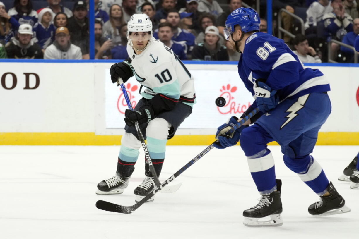 Seattle Kraken center Matty Beniers (10) and Tampa Bay Lightning defenseman Erik Cernak (81) chase a bouncing puck during the first period of an NHL hockey game Tuesday, Dec. 13, 2022, in Tampa, Fla.