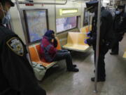 FILE - New York Police Department officers wake up sleeping passengers and direct them to the exits at the 207th Street station on the A train, Thursday, April 30, 2020, in the Manhattan borough of New York. In New York City's latest effort to address a mental health crisis on its streets and subways, Mayor Eric Adams announced Tuesday, Nov. 29, 2022, that authorities would more aggressively intervene to help people in need of treatment, saying there was "a moral obligation" to do so, even if it means providing care to those who don't ask for it.