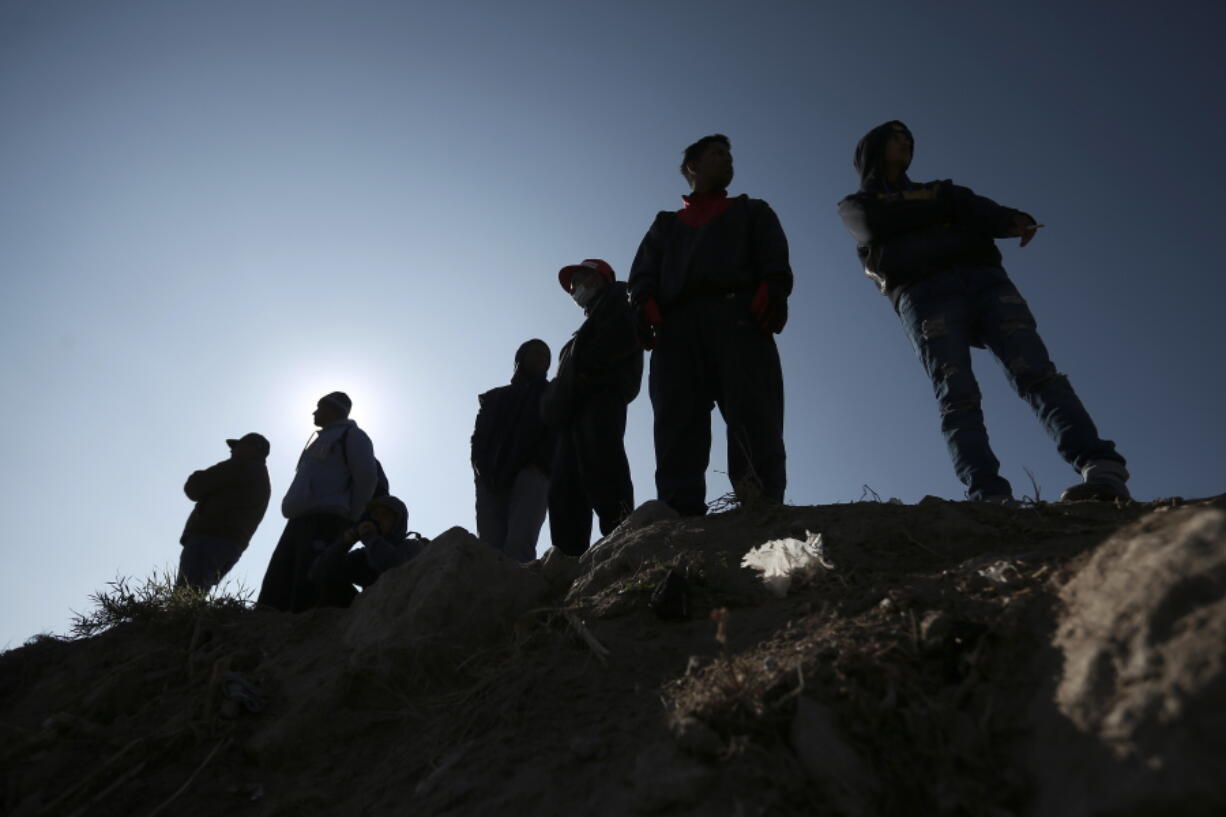 FILE - Migrants stand near the U.S.-Mexico border in Ciudad Juarez, Mexico,  Dec. 19, 2022.  The Supreme Court is keeping pandemic-era limits on people seeking asylum in place indefinitely, dashing hopes of immigration advocates who had been anticipating their end this week. The restrictions, often referred to as Title 42, were put in place under then-President Donald Trump at the beginning of the pandemic to curb the spread of COVID-19.