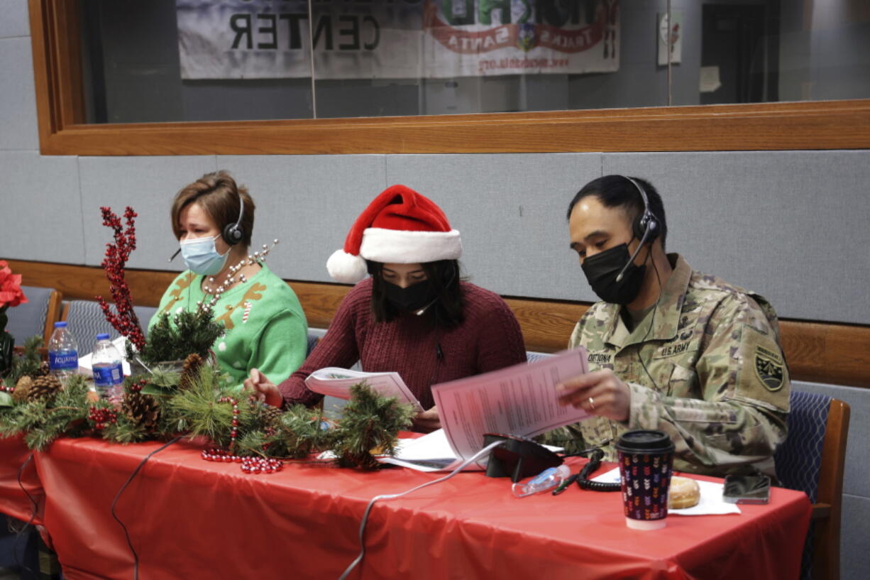 In this photo released by the U.S. Department of Defense, volunteers answer phones and emails from children around the globe during annual NORAD Tracks Santa event at Peterson Air Force Base in Colorado Springs, Colo., on Dec. 24, 2021. The U.S. military agency known for tracking Santa Claus as he delivers presents on Christmas Eve doesn't expect COVID-19 or the "bomb cyclone" hitting North America to impact Saint Nick's global travels this year. NORAD, the North American Aerospace Defense Command, is responsible for monitoring and defending the skies above North America. (Jhomil Bansil/U.S.