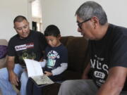 Micca Madalena, center, reads to his father, Darryl Madalena, left, and grandfather Myron Ami in his native language of Towa after getting home from school at Jemez Pueblo, N.M., Oct. 7, 2022. Darryl Madalena is advocating for more Native Americans to consider joining the organ donation rolls.