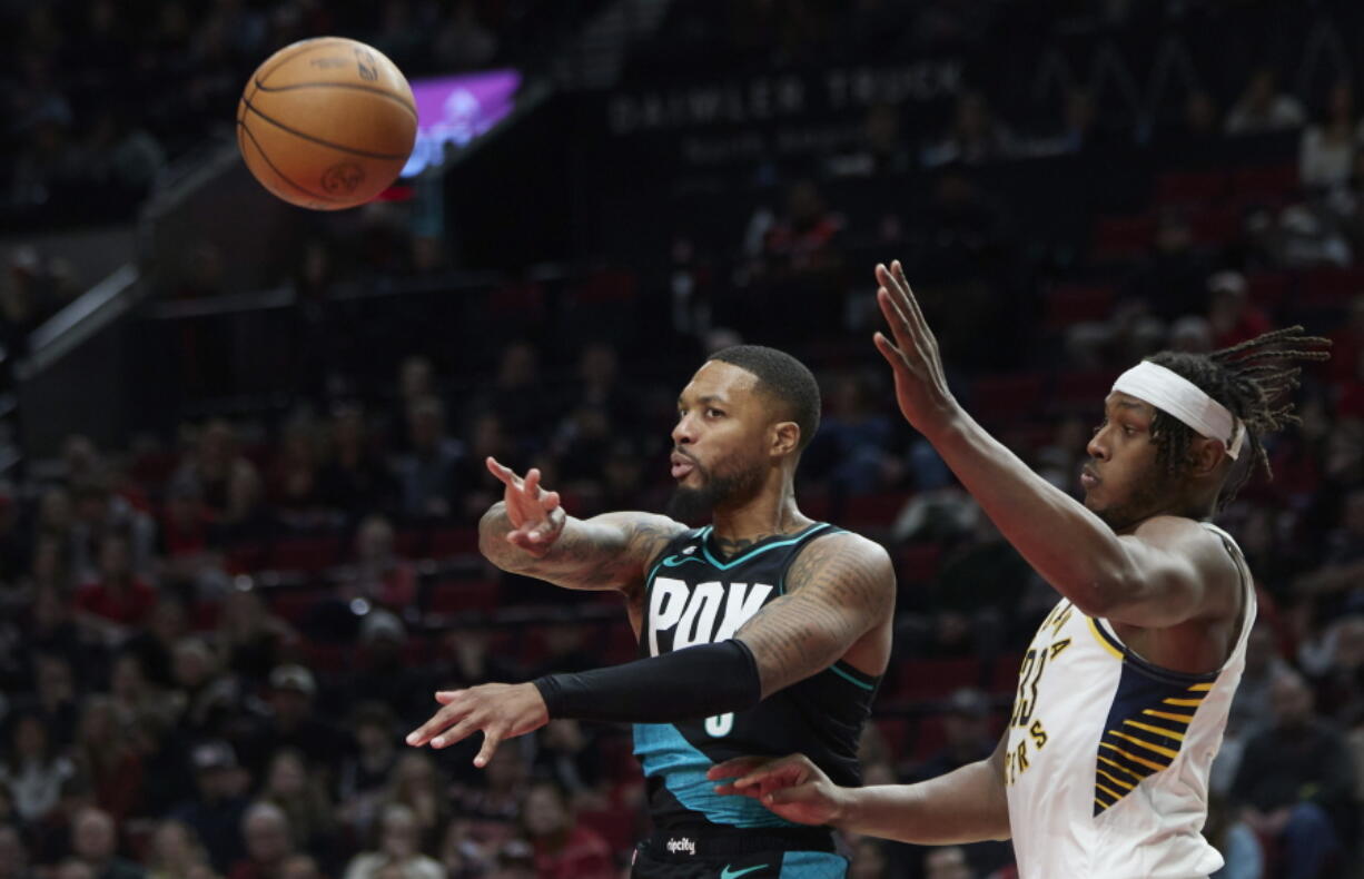 Portland Trail Blazers guard Damian Lillard, left, passes the ball away from Indiana Pacers center Myles Turner during the second half of an NBA basketball game in Portland, Ore., Sunday, Dec. 4, 2022.