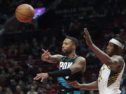 Portland Trail Blazers guard Damian Lillard, left, passes the ball away from Indiana Pacers center Myles Turner during the second half of an NBA basketball game in Portland, Ore., Sunday, Dec. 4, 2022.