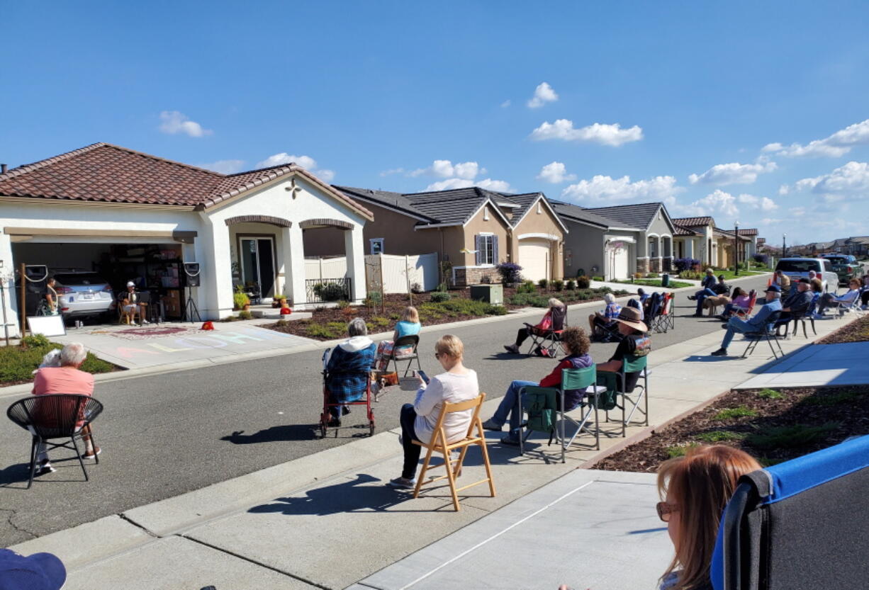 Neighbors of Lisa and Larry Neula watching them perform a Hawaiian dance in their driveway in Sacramento, Calif., in March 2022. The two began their driveway performances during lockdown and have kept them up.