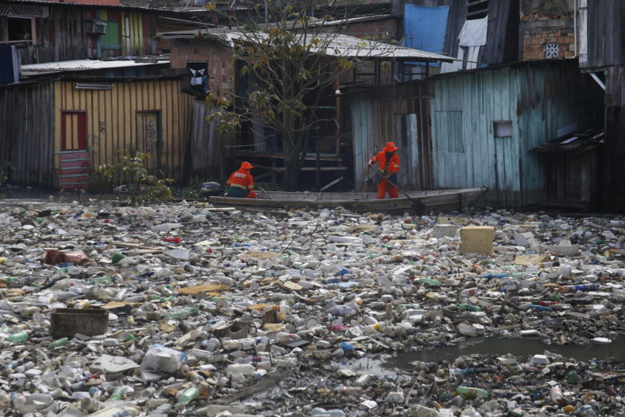 FILE - City workers remove garbage floating on the Negro River, which has a rising water level due to rain, in Manaus, Amazonas state, Brazil, June 6, 2022. More than 2,000 experts plan to wrap up early negotiations Friday, Dec. 2, on plastic pollution at one of the largest global gatherings ever to address the crisis.