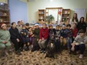 Children traumatized by the war pose for photo with an American Pit Bull Terrier "Bice" in the Center for Social and Psychological Rehabilitation in Boyarka close Kyiv, Ukraine, Wednesday, Dec. 7, 2022. Bice is an American pit bull terrier with an important and sensitive job in Ukraine -- comforting children traumatized by the war. The Center for Social and Psychological Rehabilitation is a state-operated community center where a group of people are trying to help those who have experienced a trauma after the Feb. 24 Russian invasion, and now they are using dogs like Bice to give comfort.