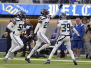 Seattle Seahawks cornerback Tariq Woolen, center, celebrates after intercepting a pass as teammates Jordyn Brooks (56) and Teez Tabor (39) watch during the first half of an NFL football game against the Los Angeles Rams Sunday, Dec. 4, 2022, in Inglewood, Calif. (AP Photo/Mark J.