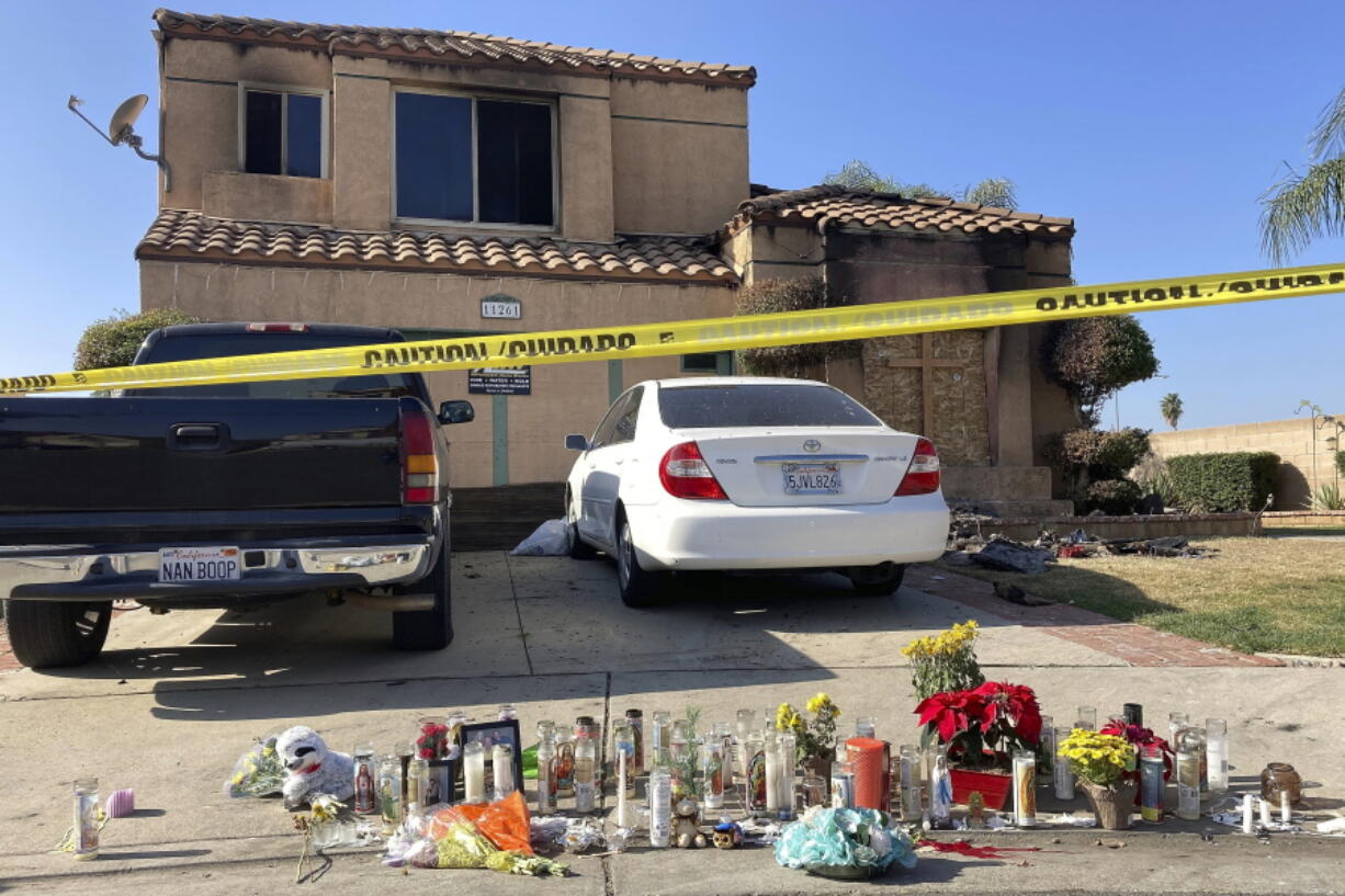 FILE - Dozens of candles sit placed on the sidewalk along with bouquets of flowers and stuffed animals outside a charred home in Riverside, Calif., on Nov. 30, 2022. The Virginia Office of the State Inspector General is investigating the state police hiring of a man who drove across the country, kidnapped a 15-year-old California girl and killed her mother and grandparents.